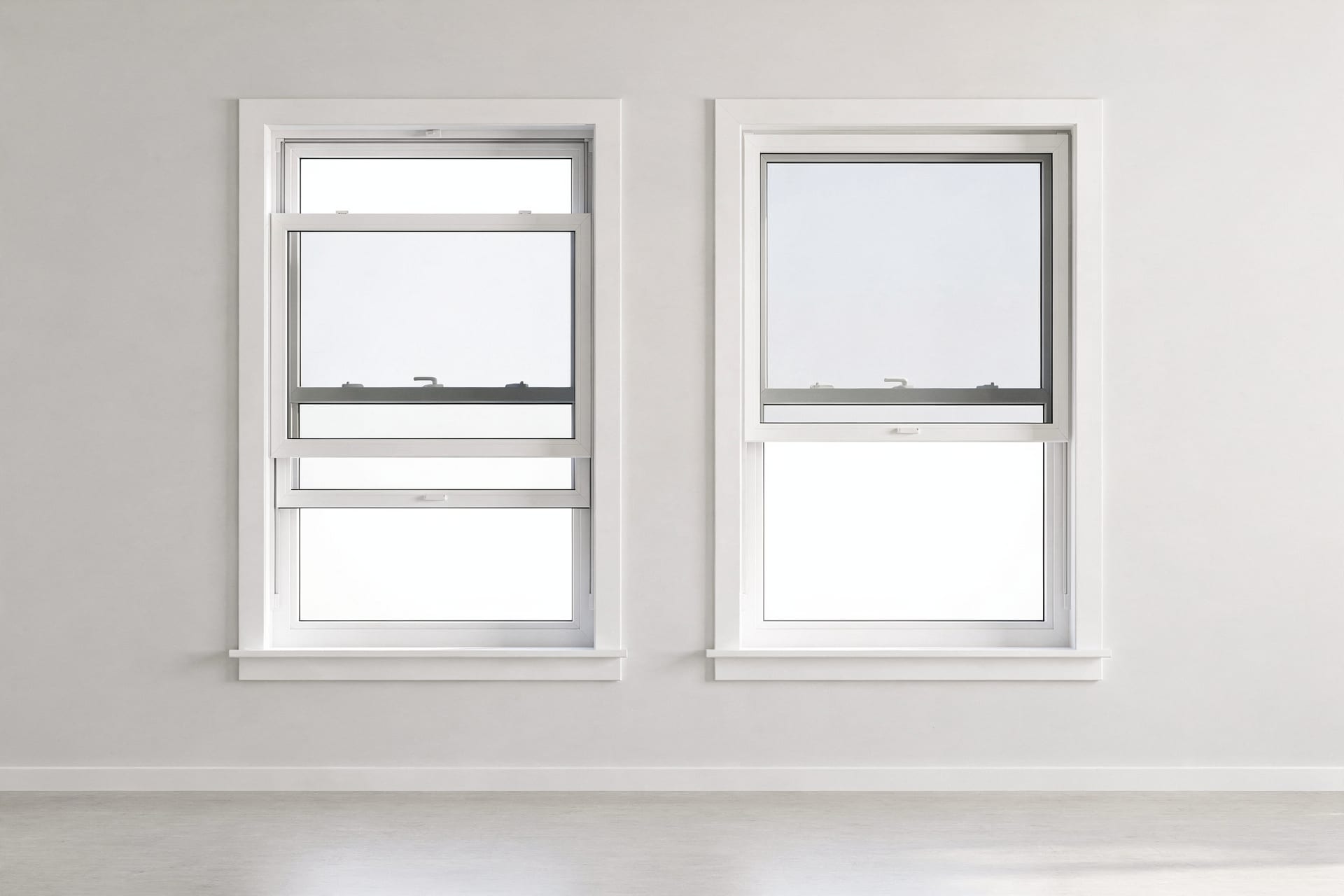 Two hung replacement windows side by side in bright, flat daylight — on the left a double-hung with both sashes visibly shifted to show each one moves, on the right a single-hung sitting closed with its top sash fixed flush — the contrast making the operational difference plain.